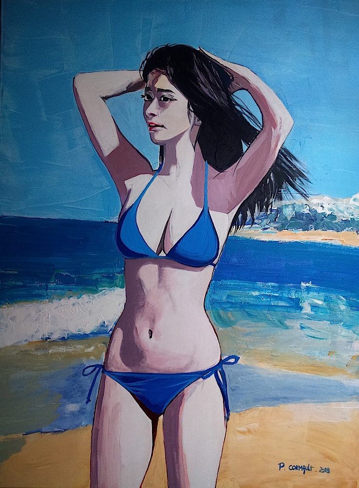 Femme en bikini bleu posant sur la plage, avec la mer à l'arrière-plan.